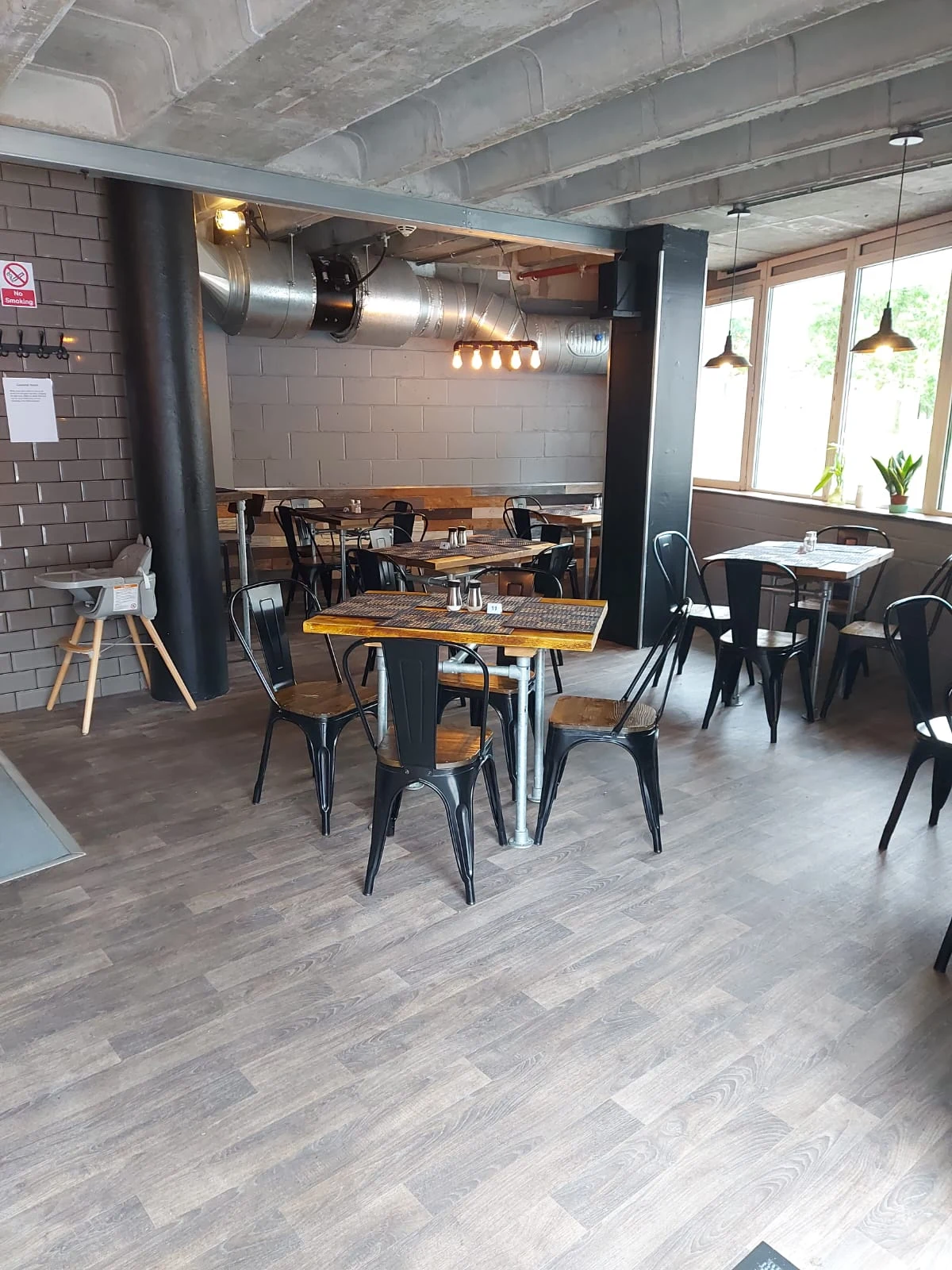 Inside KC’s restaurant at Lancaster University, with wooden tables, black chairs and warm pendant lights.